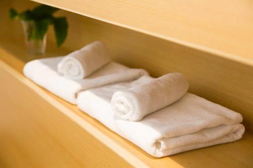 高松Kitahama Sumiyoshi的两堆毛巾,放在架子上
