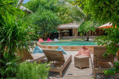 吉利特拉旺安Jati Village, Party Hostel and Bungalows的一个带桌椅的游泳池的度假酒店