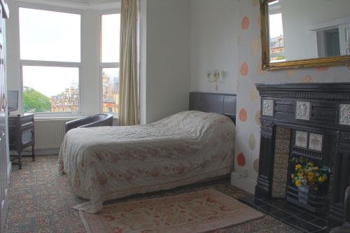 道格拉斯Ashfield Guesthouse的一间卧室配有一张床、一个壁炉和一个镜子