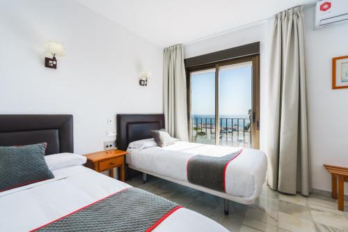 卡拉宏达Hotel El Ancla的酒店客房设有两张床和窗户。