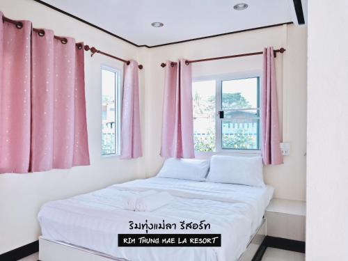 信武里府ริมทุ่งแม่ลา รีสอร์ท Rim-Thung-Mae-La-Resort的一间小卧室,配有粉红色的窗帘和一张床
