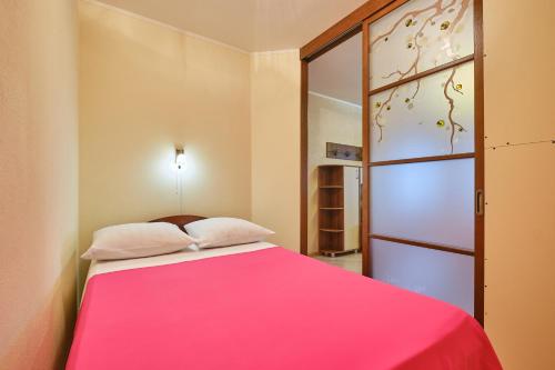 托木斯克ОК! Никитина, 20 №2的卧室配有粉红色的床和窗户。