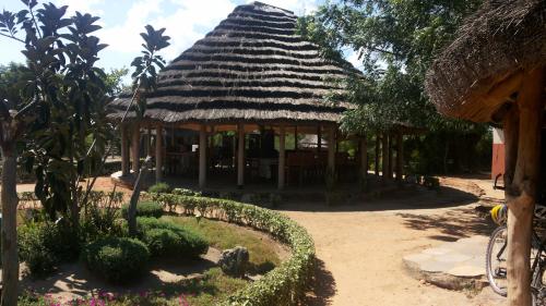 Pakwach EastHeritage Safari Lodge的一座带茅草屋顶和花园的建筑