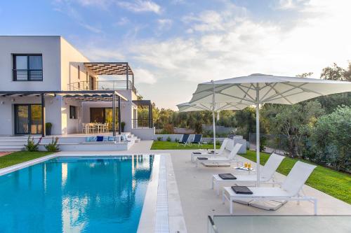 哈利库纳斯Almyra Villas的一座房子,设有游泳池、椅子和遮阳伞