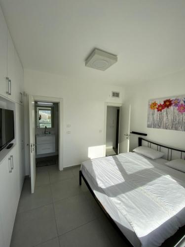 内坦亚SeaScape Terraces Netanya的一间白色卧室,配有床和电视
