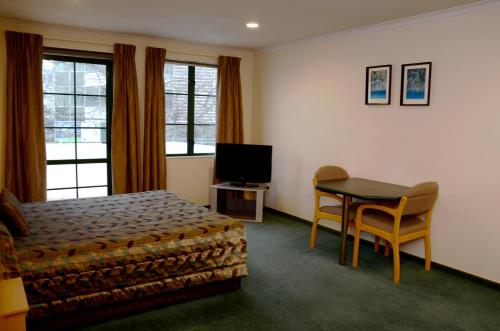 奥克兰格林兰庄园汽车旅馆的一间卧室配有一张床、一张桌子和一台电视