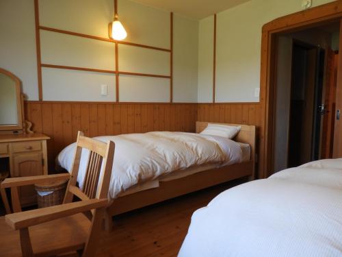 Hamanakaポロト案内舎的一间卧室配有两张床、一张桌子和一面镜子