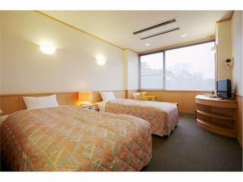 下关Genpeiso的酒店客房设有两张床和电视。