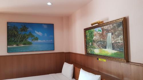 乌汶帕登酒店的一间设有一张床的客房,墙上挂着一幅画