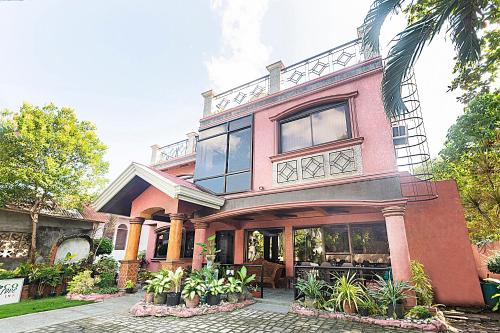 邦劳RedDoorz at Coco Grove Tourist Inn的一座大型粉红色房子,设有窗户和植物