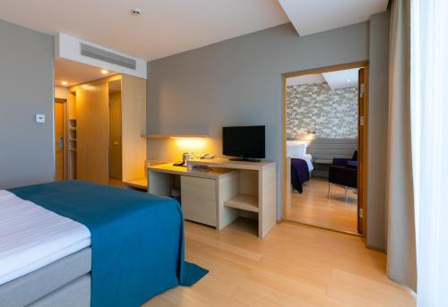 派尔努健康天堂Spa酒店的一间卧室配有一张床和一张书桌及电视