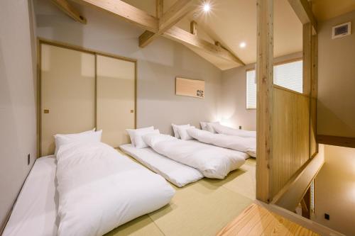 高山HOTEL WOOD TAKAYAMA的房间里的一排白色枕头