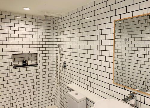 卡伦海滩阿克图尔宾馆的白色瓷砖浴室设有卫生间和镜子