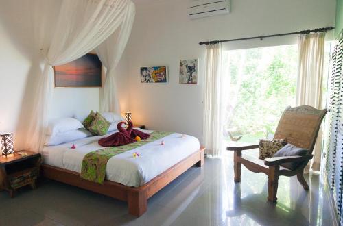 TemukusVilla Paradise Lovina的卧室配有床、椅子和窗户。