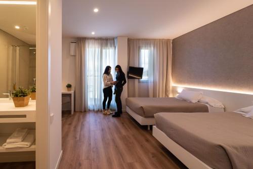 布尔戈斯拉斯特瑞安酒店的两人站在带两张床的酒店房间