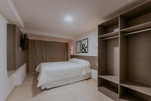 若昂佩索阿Guest Manaíra Apart Hotel的一间卧室配有床、电视和书架