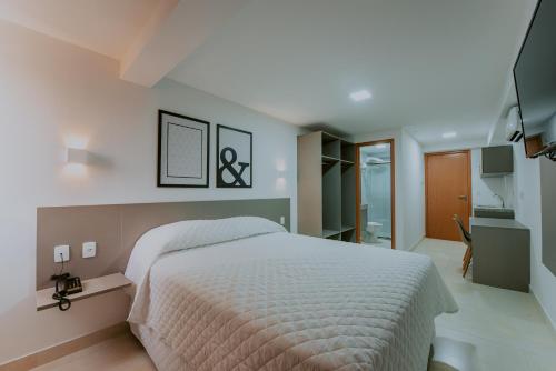 若昂佩索阿Guest Manaíra Apart Hotel的一间带白色大床的卧室和一间浴室