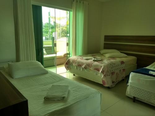 佩尼亚Pousada Ilha do Itacolomi的酒店客房设有两张床和窗户。