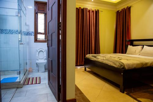 坎帕拉Dina Apartments的一间卧室设有一张床、淋浴和卫生间