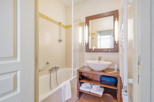 洛什皮埃尔假日科尔得利磨坊酒店的一间带水槽、浴缸和镜子的浴室
