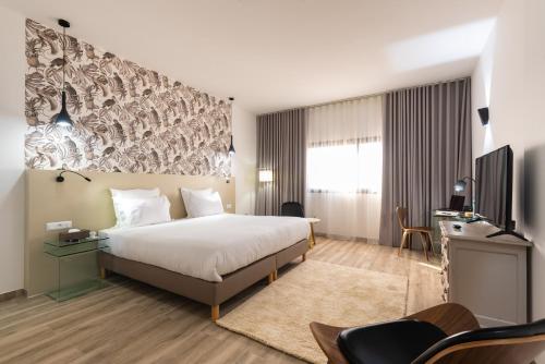 达喀尔Hotel L'Adresse Dakar的酒店客房,配有床和电视