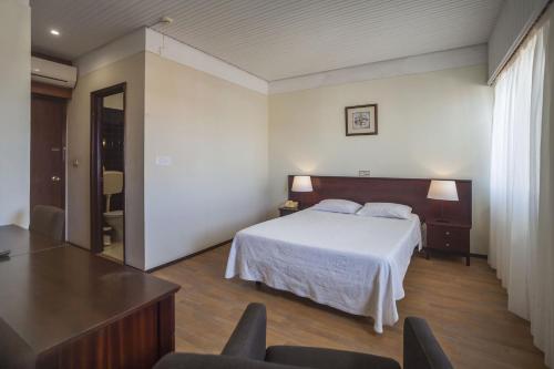蓬塔德尔加达Hotel Sete Cidades的卧室配有一张床和一张桌子及椅子