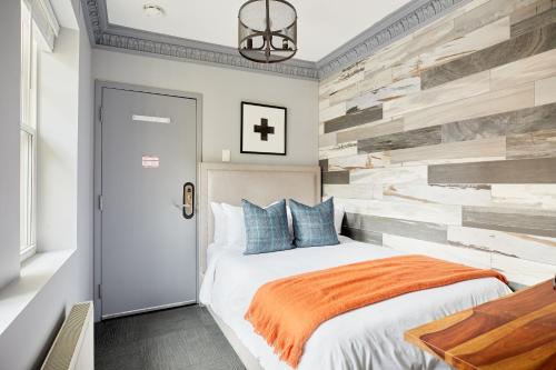 多伦多Sonder The Wellesley的一间卧室设有一张床和一堵再生木墙