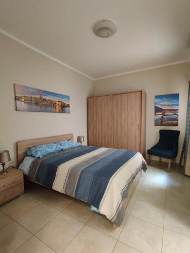 TarxienDoms Apartment的一间卧室配有一张大床和一张蓝色椅子