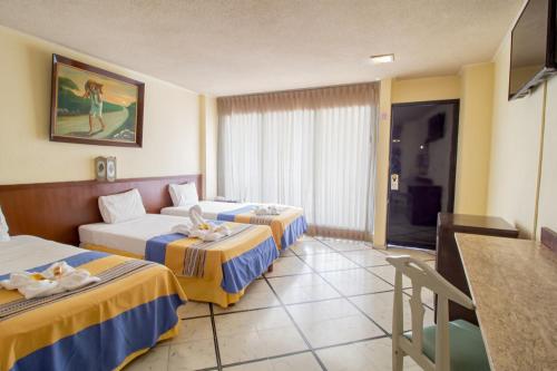 梅里达梅里达大使酒店的酒店客房设有两张床和一张桌子。
