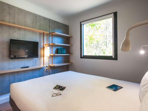 马恩河畔埃索姆ibis budget Château-Thierry的客房设有床、电视和窗户。