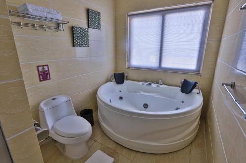 杜马格特Hotel Essencia的带浴缸、卫生间和窗户的浴室