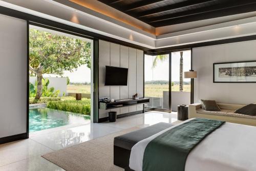 塔巴南Soori Bali的一间卧室设有一张床、一台电视和一个游泳池