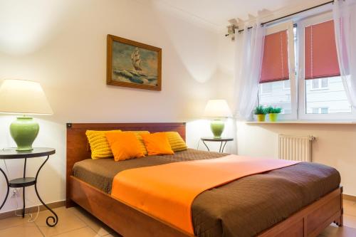 乌斯特卡Apartamenty Bałtyckie - Na Wydmie - winda, bezpłatny parking, 100m od port的一间卧室配有一张带橙色床单和两盏灯的床。