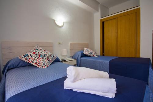 多列毛利诺斯纪乐旅馆的配有蓝色床单的客房内的两张床