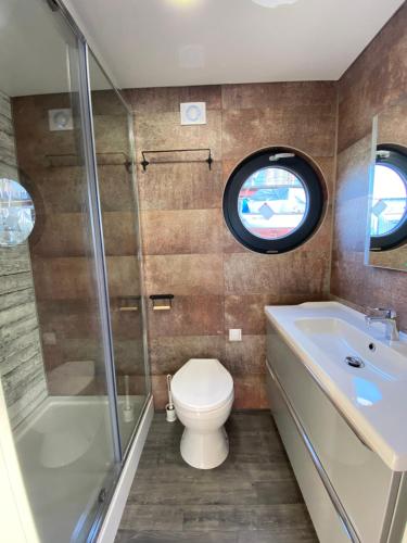 波莫瑞地区卡缅Hausboot- Domy na wodzie - Houseboat Porta Mare的一间带卫生间和浴缸的浴室以及窗户。