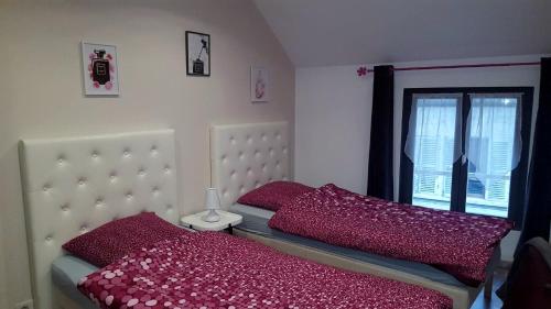 Beaumont-sur-Oise洛克公寓的一间卧室配有一张带红色枕头的床和一扇窗户