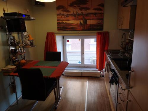 格蒙登Oranges Apartment的厨房配有桌子和带红色窗帘的窗户