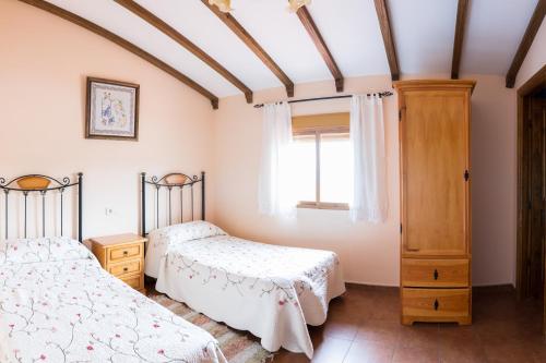 Barrado卡拉巴扎斯乡村民宿的一间卧室设有两张床和窗户。