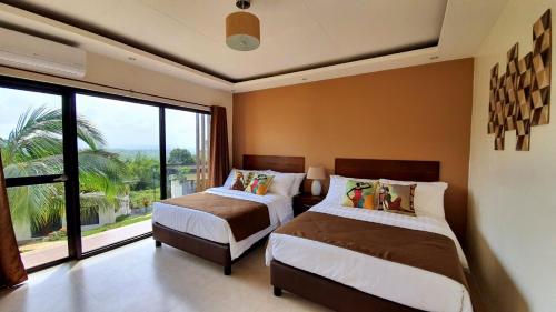 LumbanSpacio Caliraya Bed & Breakfast的一间卧室设有两张床和大窗户