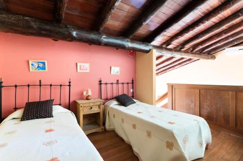 El Pinar del HierroCasa Rural La Pestilla 1的配有红色墙壁和木制天花板的客房内的两张床