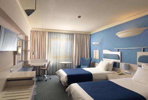 雅典Holiday Inn Athens Attica Av, Airport W., an IHG Hotel的酒店客房配有两张床和一张书桌