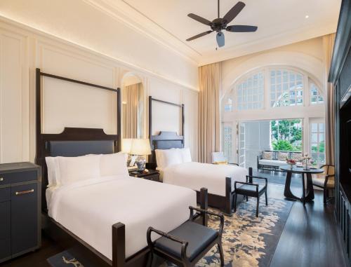 新加坡新加坡莱佛士酒店的一间卧室配有两张床和一张桌子及椅子