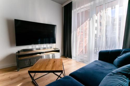 弗罗茨瓦夫Apartament Małopanewska Wrocław Centrum的客厅配有蓝色的沙发和平面电视。