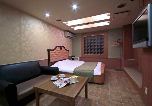 四日市Hotel Mio Resort ( Adult Only)的酒店客房配有床、沙发和桌子。