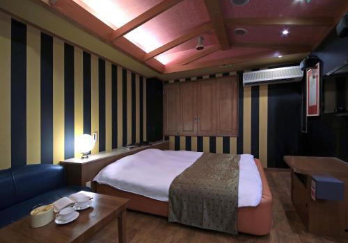四日市Hotel Mio Resort ( Adult Only)的一间卧室配有一张床、一张沙发和一张桌子