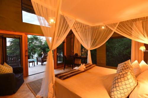 MafutaRoyal Zambezi Lodge的一间卧室配有带窗帘的床和庭院。