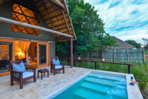 MafutaRoyal Zambezi Lodge的一个带两把椅子的游泳池以及一座房子