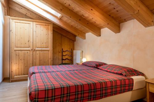 博尔米奥斯特雷狄内维小木屋酒店的一间带一张床的卧室,位于带木制天花板的房间内