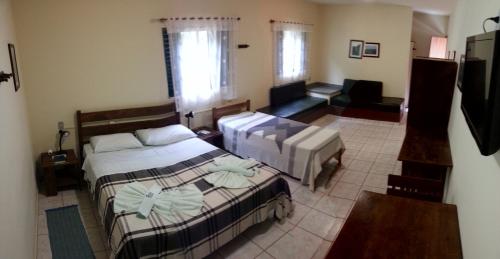 圣罗克迪米纳斯Pousada Barcelos的一间带两张床的卧室和一间客厅