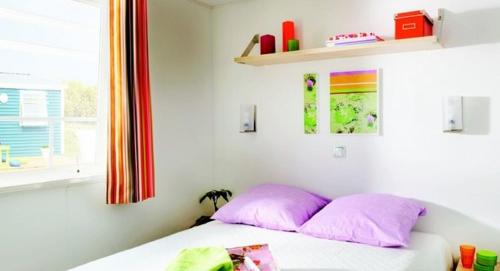 鲁瓦扬Camping Les Chèvrefeuilles - Maeva的一间卧室配有带粉红色枕头的床和窗户。